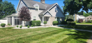 Medium sized home on a corner lot with professional landscaping surrounding home. Trimmed shrubs and decorative trees planted in bed with white stone.