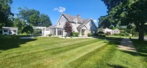 Medium sized home on a corner lot with professional landscaping surrounding home. Evergreen shrubs and decorative trees planted in bed with white stone.