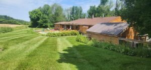 Back yard of 2 acre lawn mowed with stripes toward house with pool in back of country house.