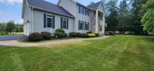 Large home with trimmed shrubs and maintained mulch landscape bed with lawn just mowed.