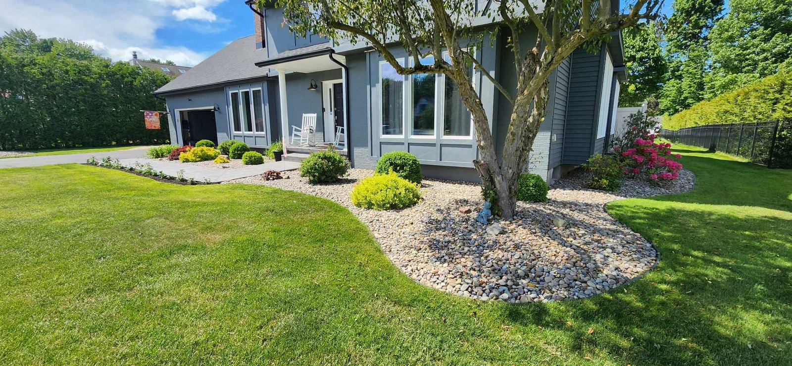 Large home with rock landscape bed and flowering shrubs